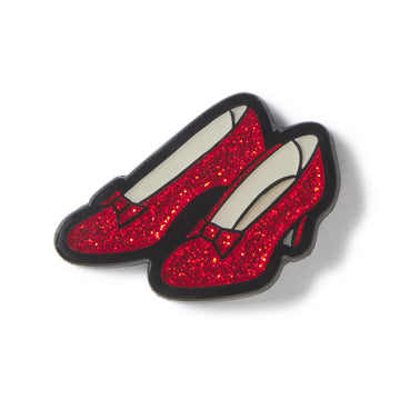 Red glittery shoes with black outline on a white background. Dorothy's ruby slippers lapel pin from The Wizard of Oz
